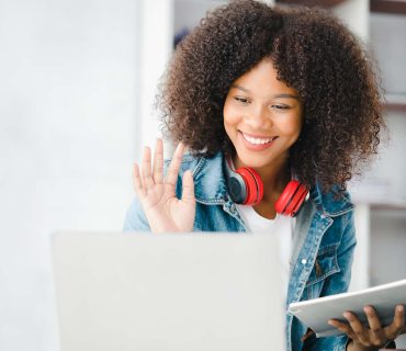 American teenage girl having a remote video call with friend on laptop, she is a student studying online at home, university student studying online, online web education concept.